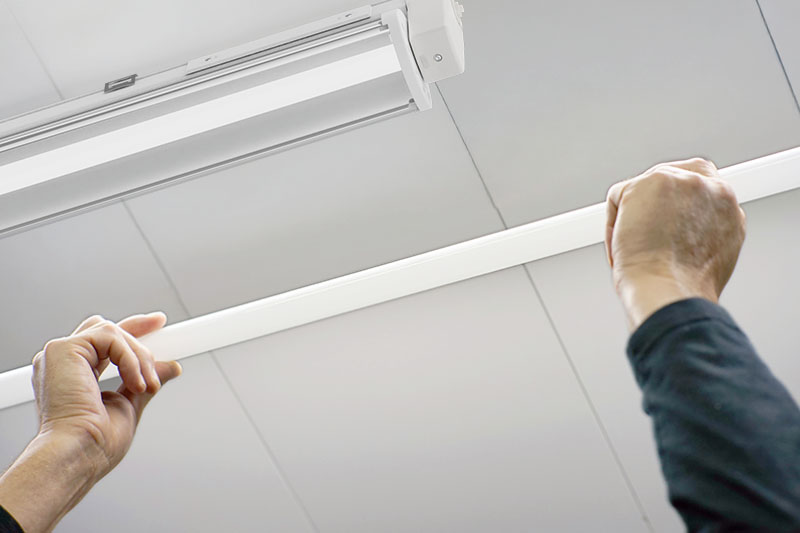Mann hält Leuchtstoffröhre vor LED-Lampe
