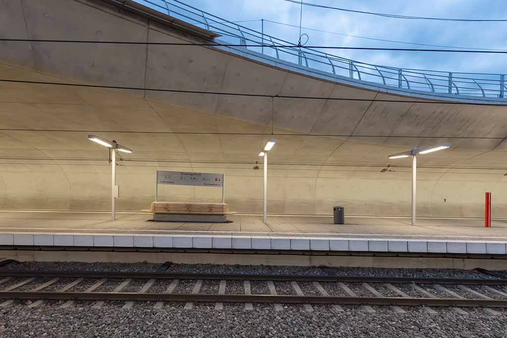 Stadtbahn-Haltestelle Staatsgalerie in Stuttgart, Blick auf den geräumigen, modernen Bahnsteig mit gleichmäßig beleuchteten LED-Leuchten und gewölbter Betonwand im Hintergrund.