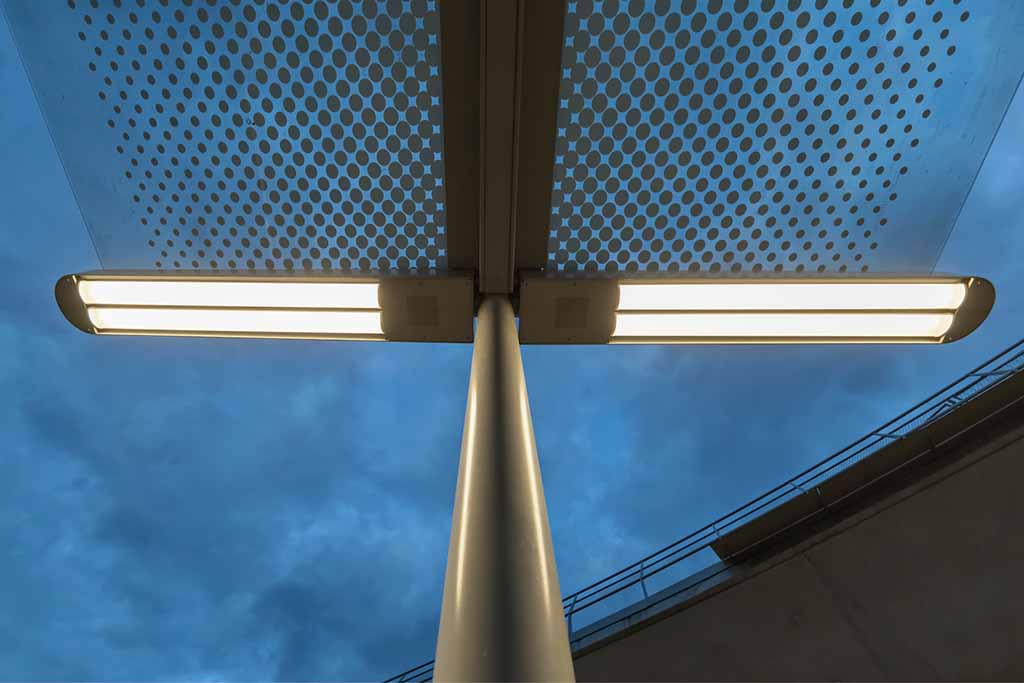 Detailansicht einer NORKA ERFURT LED-Leuchte an der Stadtbahn-Haltestelle Staatsgalerie Stuttgart, montiert auf einem Mast vor dem Abendhimmel