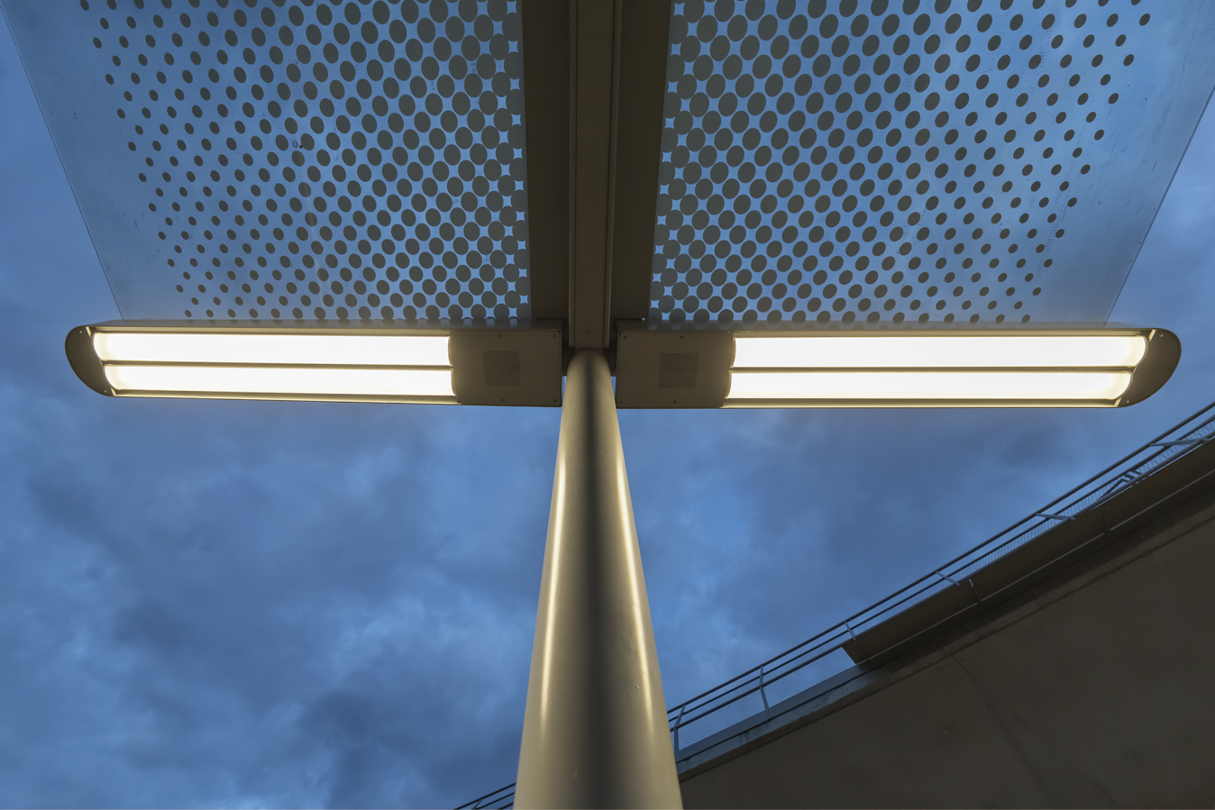 Vue détaillée d'un luminaire LED NORKA ERFURT à l'arrêt de tramway Staatsgalerie Stuttgart, monté sur un mât devant le ciel du soir.