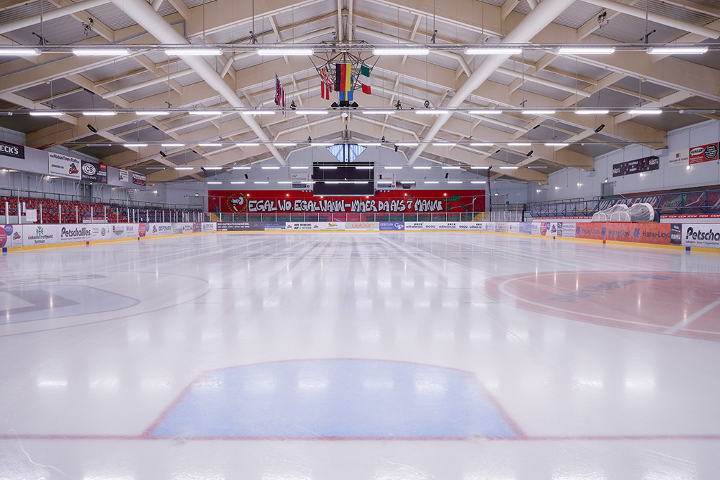 3. LED-beleuchteten Eishalle mit Hallenbeleuchtung und Zuschauertribünen im Hintergrund.